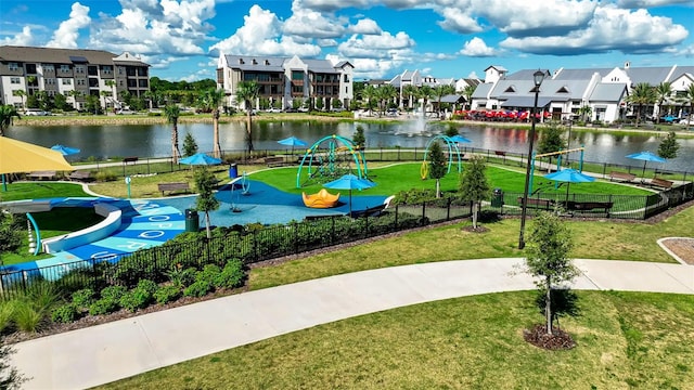 view of community featuring a water view, fence, and a lawn