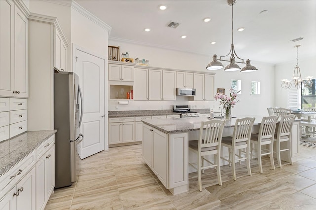 kitchen featuring crown molding, visible vents, appliances with stainless steel finishes, a kitchen island with sink, and a kitchen bar