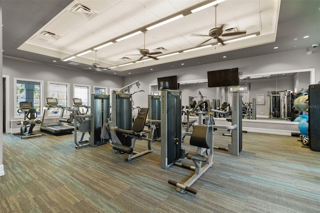 exercise room with carpet floors, visible vents, a raised ceiling, and a ceiling fan