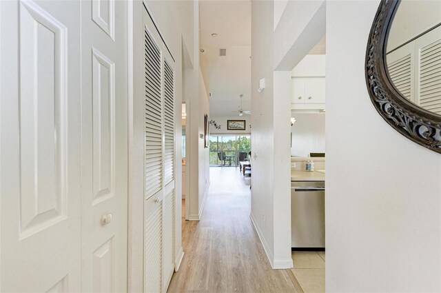 corridor featuring a towering ceiling and light hardwood / wood-style flooring