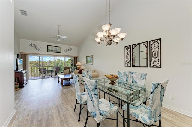 dining room with light wood finished floors, baseboards, visible vents, high vaulted ceiling, and ceiling fan with notable chandelier