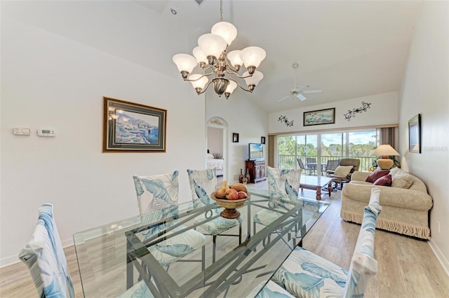 dining room featuring high vaulted ceiling, ceiling fan with notable chandelier, baseboards, and wood finished floors