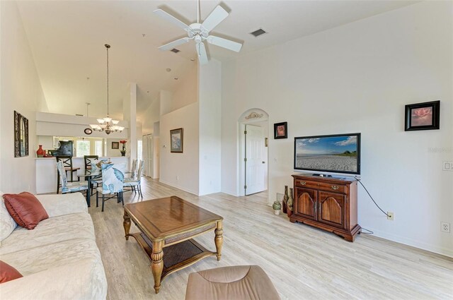 living room with light hardwood / wood-style floors, high vaulted ceiling, and ceiling fan with notable chandelier