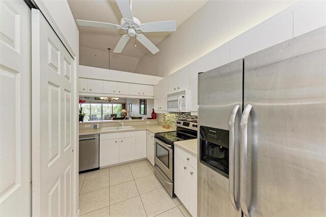 kitchen with lofted ceiling, white cabinets, ceiling fan, light tile patterned flooring, and stainless steel appliances