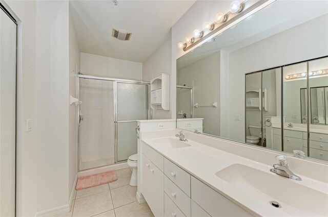 bathroom featuring toilet, an enclosed shower, vanity, and tile patterned floors