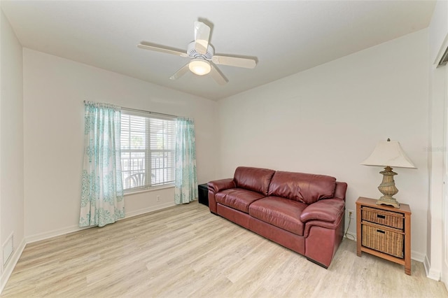 living area featuring a ceiling fan, baseboards, and light wood finished floors