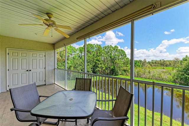 sunroom featuring a water view and ceiling fan