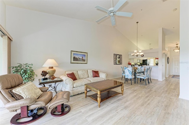 living room featuring high vaulted ceiling, light wood-type flooring, and ceiling fan with notable chandelier