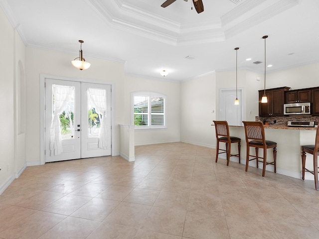 tiled entrance foyer with crown molding, ceiling fan, french doors, and a tray ceiling