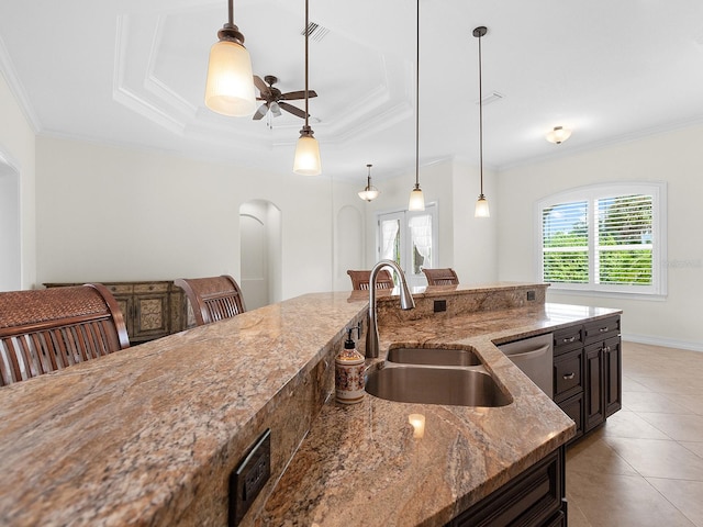 kitchen with light stone countertops, a tray ceiling, hanging light fixtures, sink, and light tile patterned flooring