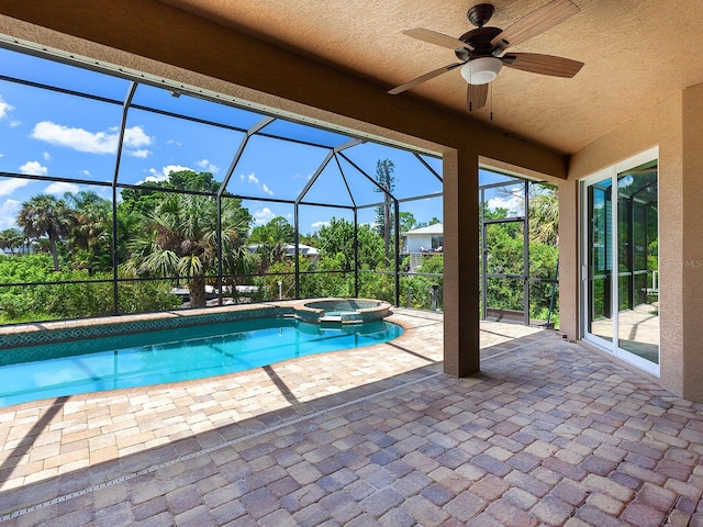 view of pool featuring glass enclosure, an in ground hot tub, ceiling fan, and a patio area