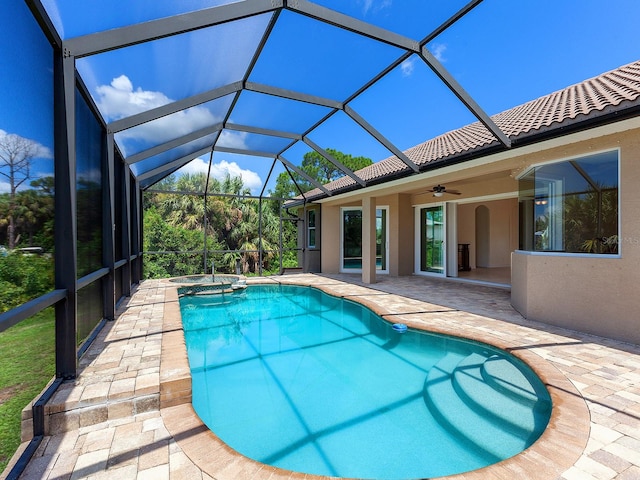 view of pool featuring glass enclosure, a patio area, and ceiling fan