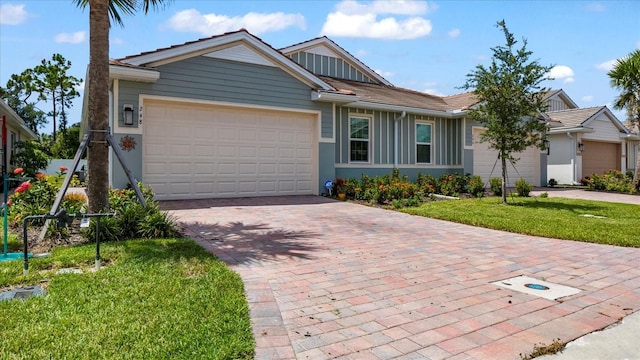 ranch-style house with decorative driveway, an attached garage, a tile roof, and a front yard