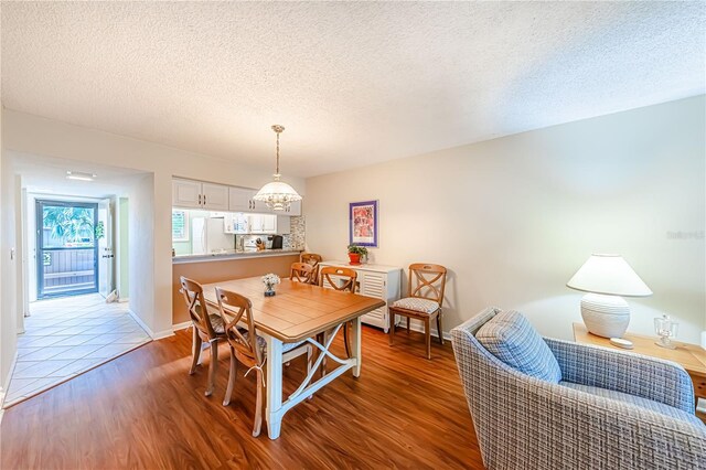 dining area featuring a textured ceiling, an inviting chandelier, and hardwood / wood-style flooring