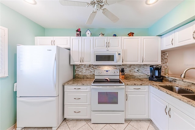 kitchen featuring white appliances, light stone countertops, white cabinetry, sink, and ceiling fan