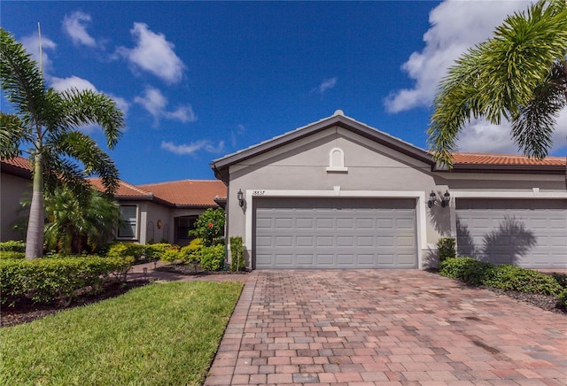 view of front of home with a tile roof, decorative driveway, a garage, and stucco siding