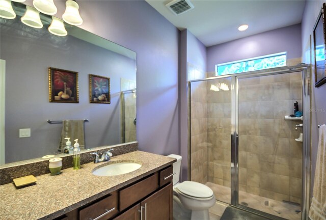 bathroom featuring vanity, toilet, and an enclosed shower