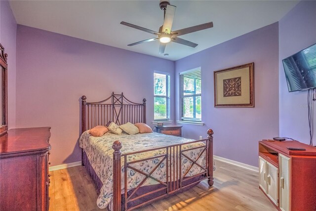 bedroom with light wood-style flooring, a ceiling fan, and baseboards