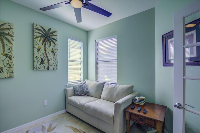 living area featuring baseboards and ceiling fan