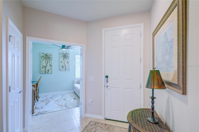 foyer entrance with light tile patterned floors, a ceiling fan, and baseboards