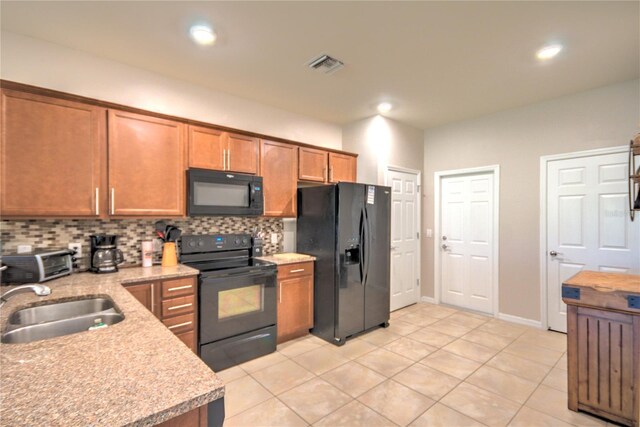 kitchen featuring visible vents, backsplash, black appliances, and brown cabinets