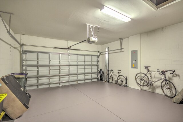 garage with electric panel, a garage door opener, and concrete block wall