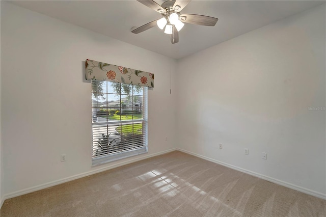 spare room with baseboards, a ceiling fan, and light colored carpet