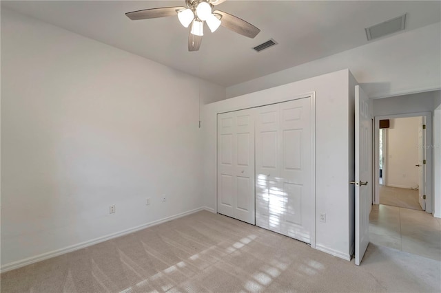 unfurnished bedroom featuring a ceiling fan, a closet, visible vents, and light colored carpet