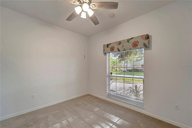 spare room featuring light carpet, ceiling fan, and baseboards