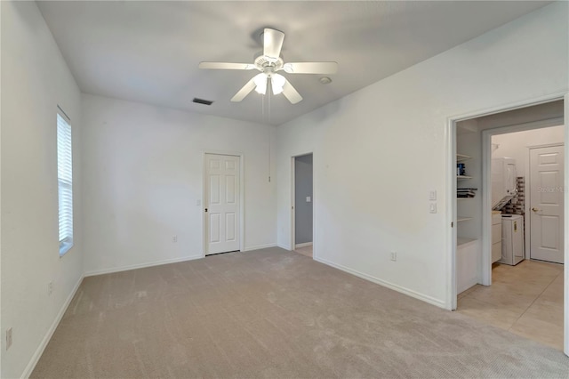 unfurnished room featuring a ceiling fan, light colored carpet, visible vents, and baseboards