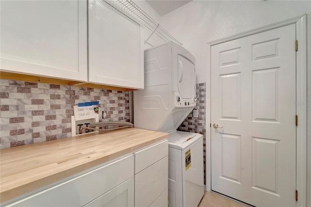 washroom featuring stacked washer / dryer, cabinet space, and light tile patterned floors