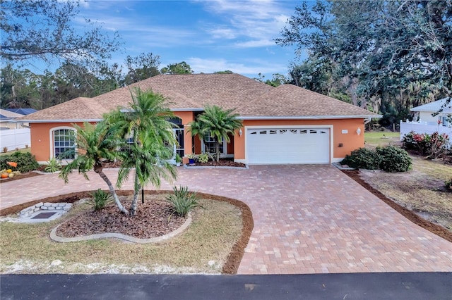 view of front of house with decorative driveway, an attached garage, and stucco siding