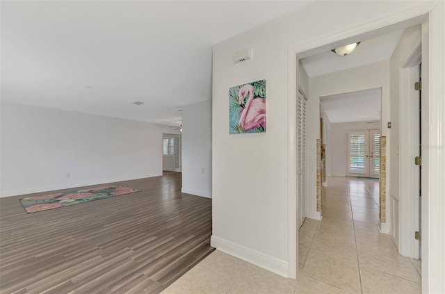 hallway with light wood-type flooring and french doors