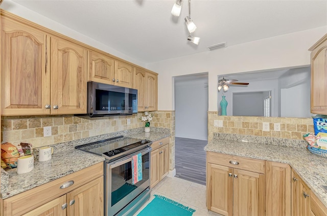 kitchen featuring appliances with stainless steel finishes, light stone counters, decorative backsplash, and ceiling fan