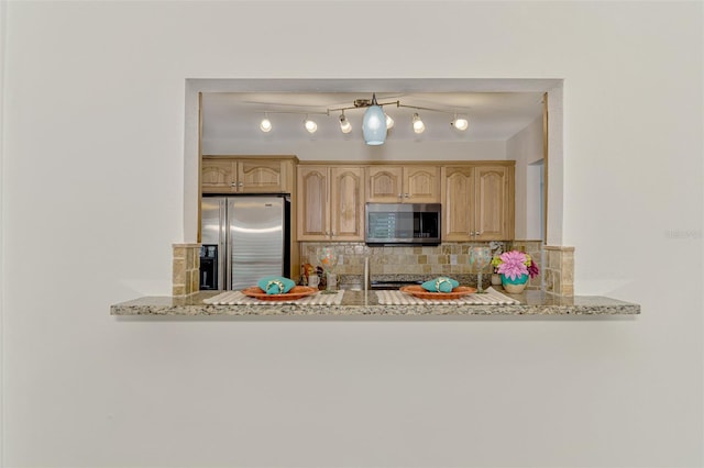 kitchen with light brown cabinetry, tasteful backsplash, stainless steel appliances, and light stone countertops