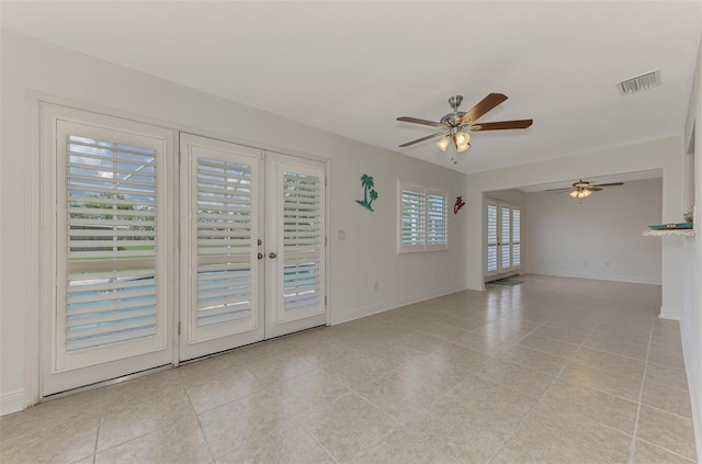 tiled empty room featuring ceiling fan and french doors