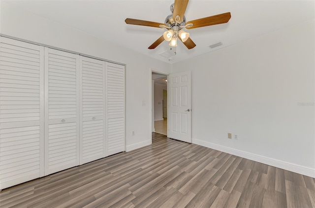 unfurnished bedroom with wood-type flooring, ceiling fan, and a closet