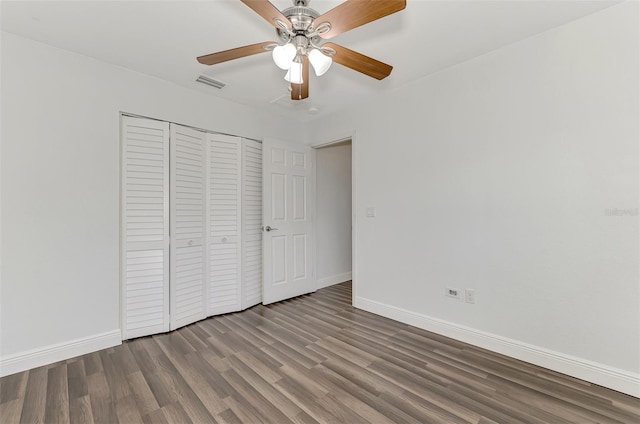 unfurnished bedroom with dark wood-type flooring, a closet, and ceiling fan