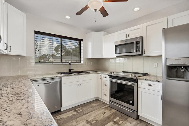 kitchen featuring light wood-type flooring, stainless steel appliances, sink, ceiling fan, and white cabinets