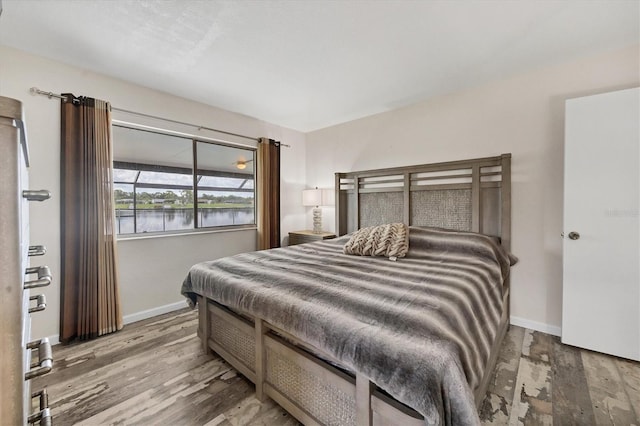 bedroom featuring a water view and hardwood / wood-style floors