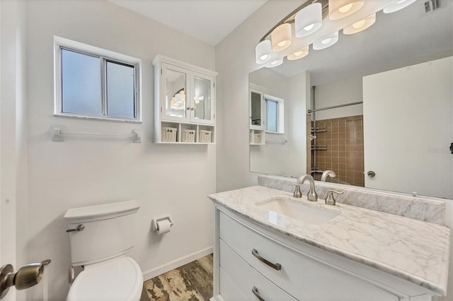 bathroom with vanity, toilet, a tile shower, and hardwood / wood-style flooring