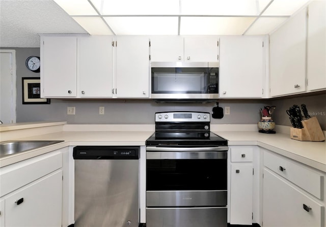 kitchen with sink, white cabinets, a textured ceiling, and stainless steel appliances