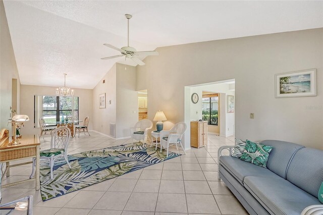 living room featuring ceiling fan with notable chandelier, a textured ceiling, a wealth of natural light, and light tile patterned flooring