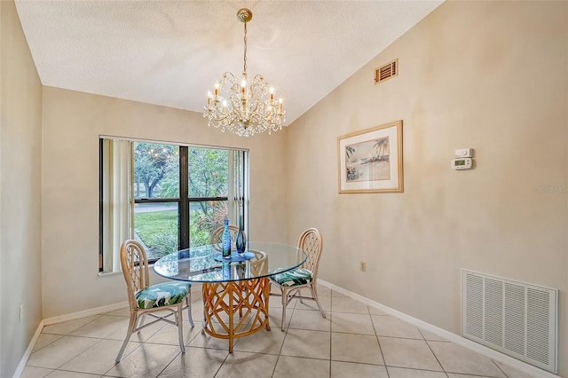 tiled dining room with a textured ceiling, vaulted ceiling, and a chandelier