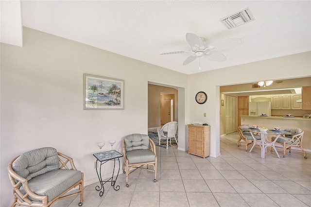 living area featuring light tile patterned floors, ceiling fan, visible vents, and baseboards