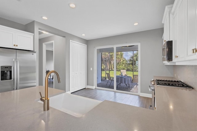 kitchen with white cabinets, appliances with stainless steel finishes, wood-type flooring, and sink