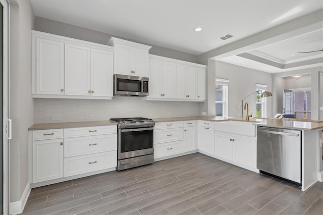 kitchen with stainless steel appliances, sink, kitchen peninsula, and light hardwood / wood-style flooring