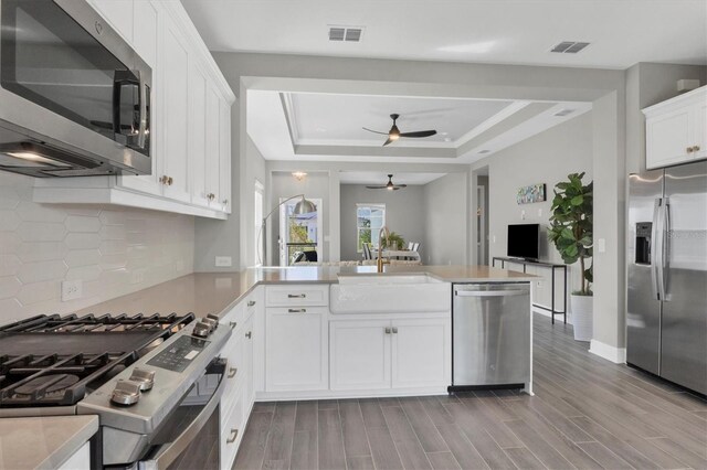 kitchen with white cabinetry, light hardwood / wood-style flooring, kitchen peninsula, and stainless steel appliances