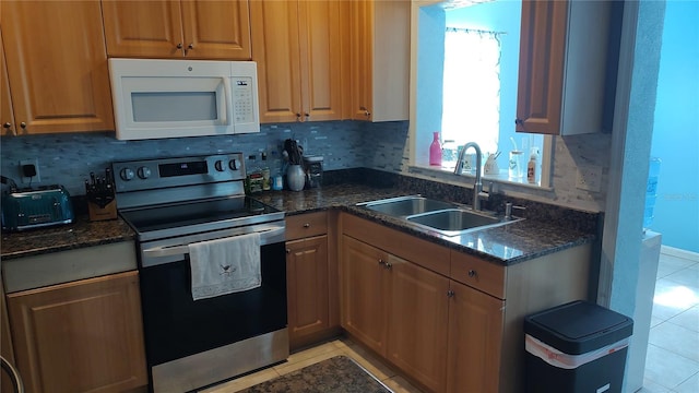 kitchen featuring sink, light tile patterned floors, backsplash, and stainless steel range with electric stovetop