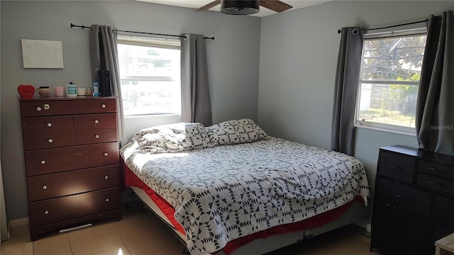 bedroom featuring multiple windows, light tile patterned flooring, and ceiling fan